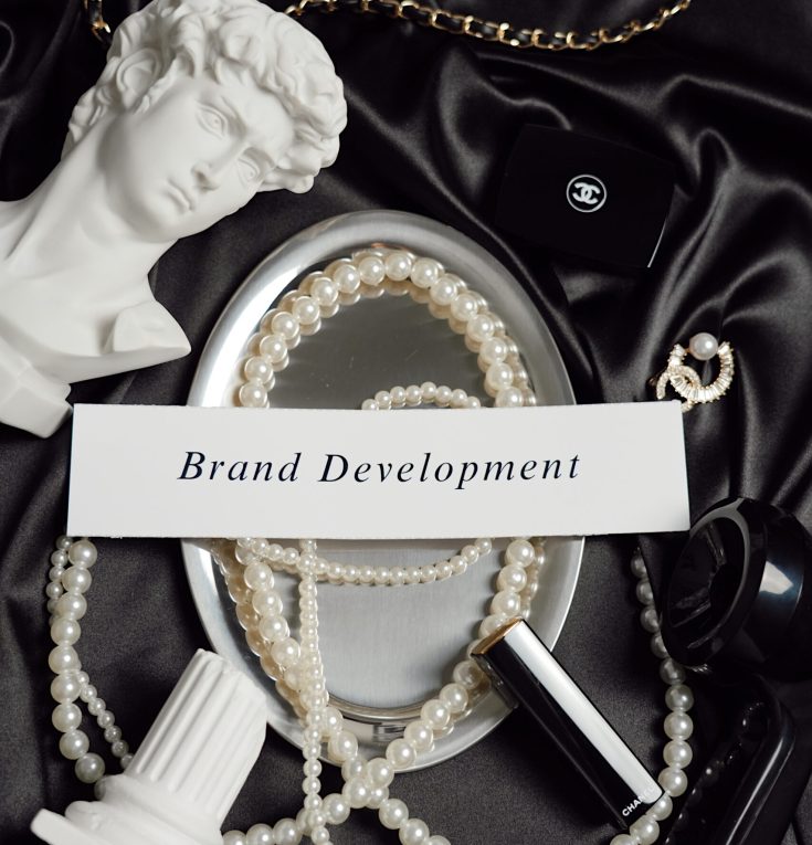 Elegant flat lay with pearls, sculpture, and a card reading “Brand Development,” symbolizing luxury branding and creative direction.